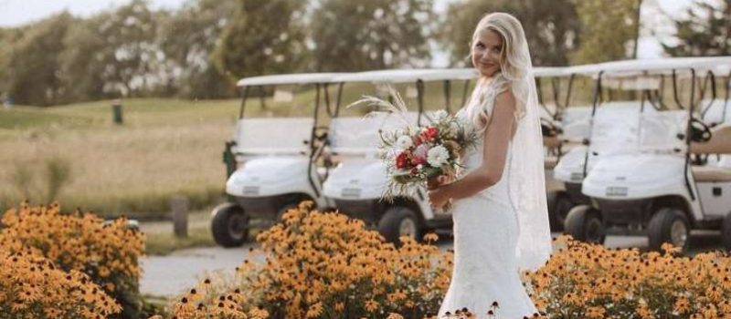 bride standing in flowers near gold carts at Par 5 Resort in Mishicot, WI