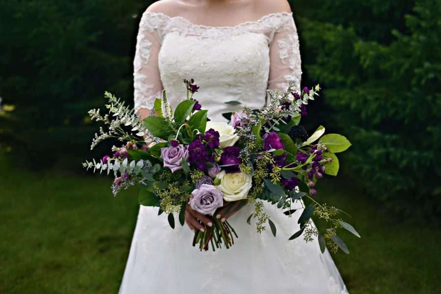 Beautiful bridal bouquet in shades of deep violet and lavender with lush greenery.