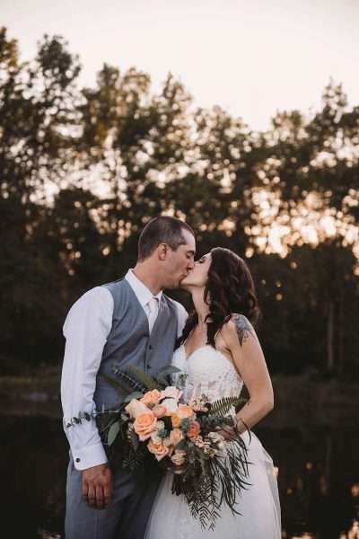Bride holding lush bouquet kissing groom