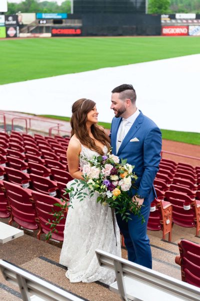 Bride and groom pose in stands at the Fox Cities Stadium in Appleton, WI.
