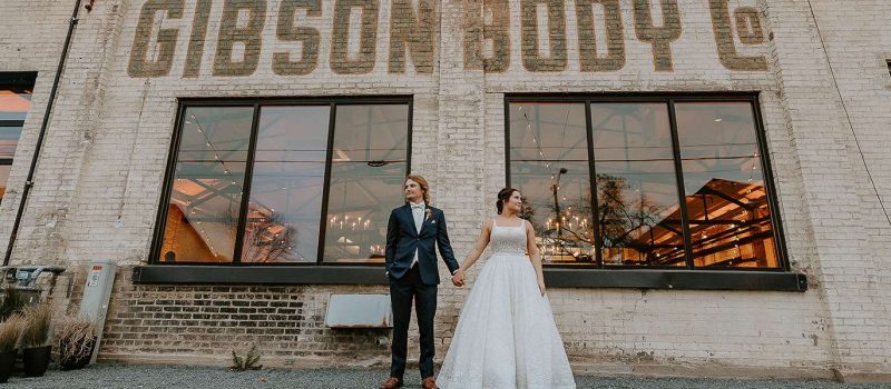 Couple pose outside the Gibson Social Club at their Downtown Oshkosh Wedding