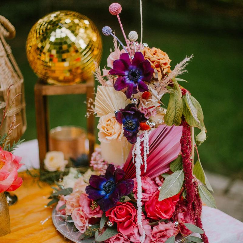 Wedding cake by the Cupcake Couture adorned with vibrant hued flowers