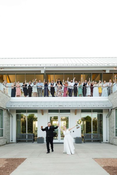 Wedding guests on balcony cheer as the bride and groom walk out the lower level at The Donald and Carol Kress Pavilion in Door County.