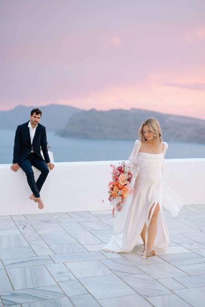 Bride walks on terrace in Greece.