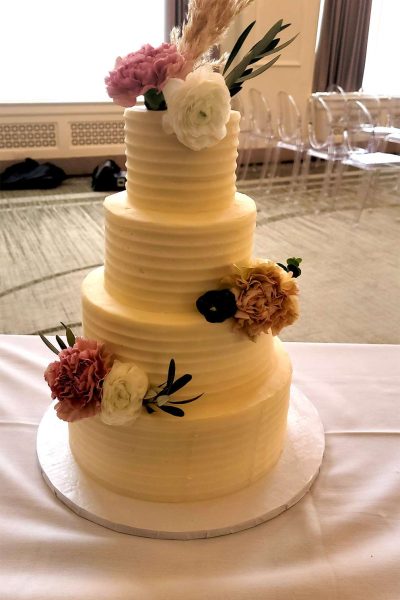 4 Tiered wedding cake adorned with assorted flowers.